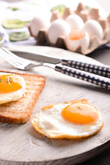 Toasted bread with tasty fried eggs on wooden board