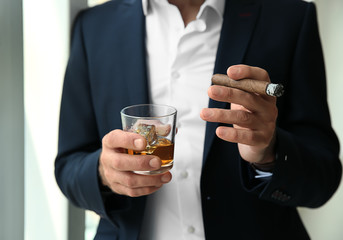 Senior man drinking whiskey and smoking cigar, closeup