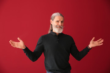 Emotional senior man after making mistake on color background