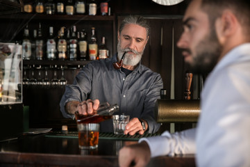 Senior barman serving client in pub