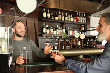 Young barman serving client in pub