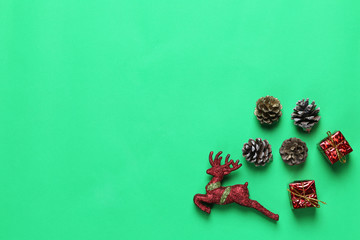 Pine cones and doll deer on a green paper background.