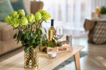 Vase with beautiful green roses on wooden table in room