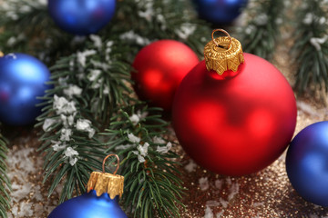 Christmas balls with fir tree branches on color background, closeup