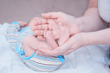 The tiny feet of the newborn in the hands of the mother. The concept of motherhood and child...
