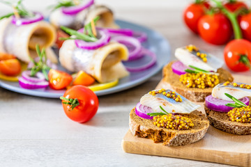Sandwich with pieces of marinated herring with red onion and french mustard