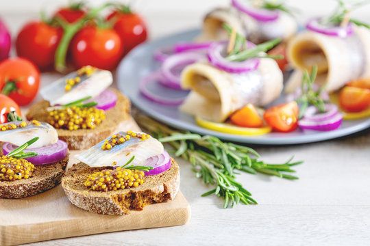 Sandwich with pieces of marinated herring with red onion and french mustard