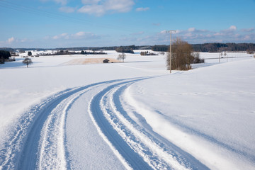 winterliche kurvige Landstraße in der verschneiten Landschaft