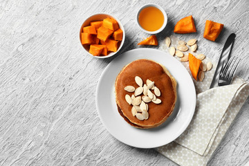 Plate with hot tasty pancakes and pumpkin seeds on light table