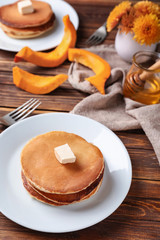 Stack of hot pumpkin pancakes with butter on plate