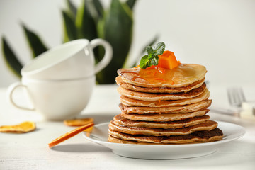 Stack of hot tasty pancakes with pumpkin on plate