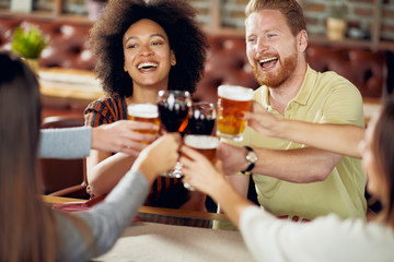 Friends making a toast while sitting in restaurant. Multi-ethnic group.