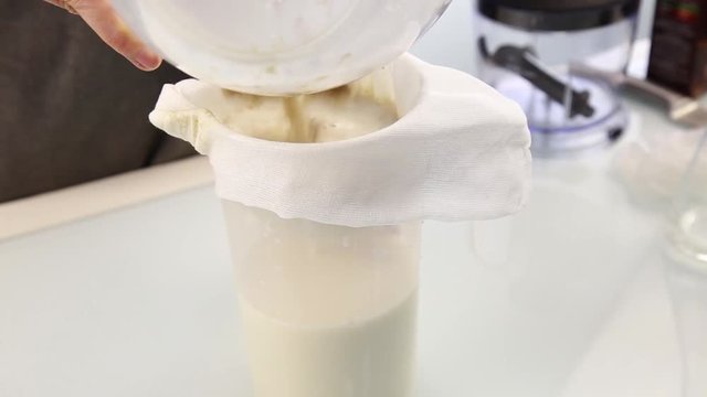 Hands of a young woman squeezing the organic milk from bag or cheese cloth. Healthy food concepte