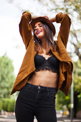 Smiling young woman with hat in a sunny day in the street