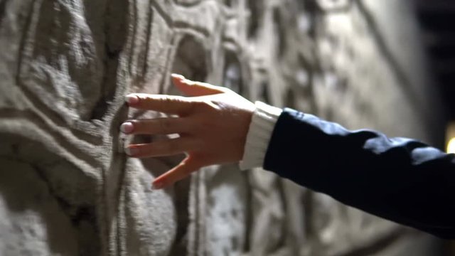 Girl is Walking along Wall in Dark Alley and Gently Grazes Touching it with Hand, cinematic dof