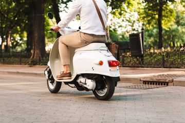 Young business man walking outdoors on scooter.