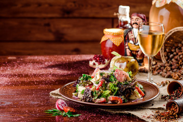 vegetable salad with tomatoes, cheese and bell peppers on a brown plate and a glass of white wine on a dark wooden background. beautiful composition. Georgian cuisine. close-up