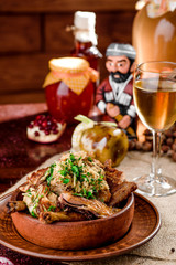 national Georgian cuisine. chicken thighs in a brown plate and a glass of white wine in a beautiful composition on a burlap on a wooden table. close-up. photo series