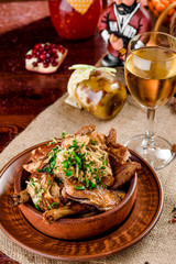 national Georgian cuisine. chicken thighs in a brown plate and a glass of white wine in a beautiful composition on a burlap on a wooden table. close-up. photo series