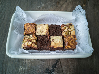 Chocolate, walnut and raspberry brownie squares on the top of wooden table.