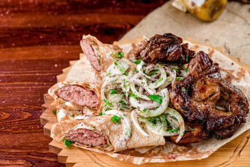 Georgian cuisine. grilled meat with onions, pita bread with sausages and a glass of rad wine on a wooden board on a burlap. top view. flat lay. close-up.