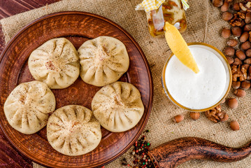 national Georgian dish. khinkali on a brown clay plate and beer with white foam on sackcloth close-up, top view. Georgian cuisine