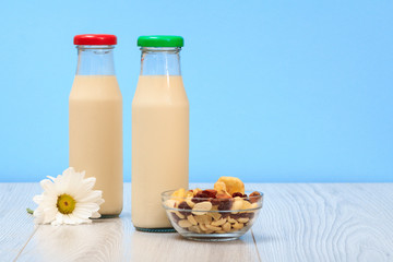Two bottles of milk with red and green cap and bowl with muesli.