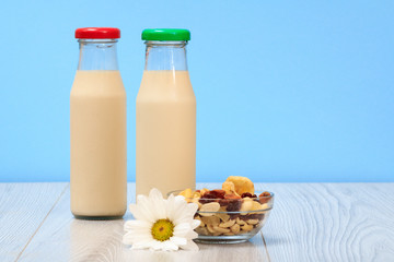 Two bottles of milk with red and green cap and bowl with muesli.