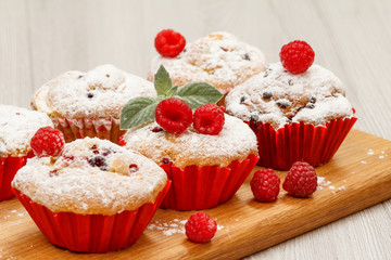 Homemade fruit muffins sprinkled with powdered sugar on board.