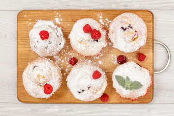 Homemade fruit muffins sprinkled with powdered sugar on board.