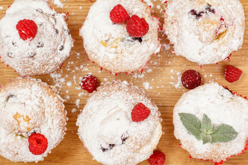 Homemade fruit muffins sprinkled with powdered sugar on board.