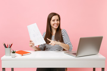 Successful woman pointing index finger on paper documents, working on project while sitting at...
