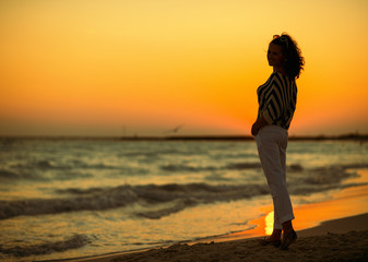 Fototapeta premium Full length portrait of modern woman on seashore in evening