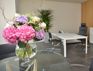 Ufficio con tavolo ricreativo in vetro e mazzo di fiori, fuoco selettivo