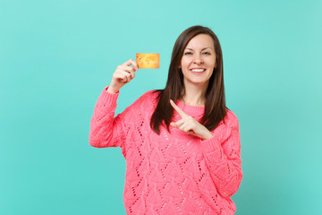 Attractive young woman in knitted pink sweater pointing index finger on credit card in hand...