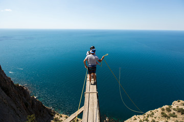 Rope jumping off a cliff with a rope in the water. The ocean. Sea. Mountain