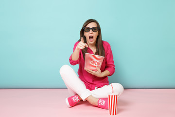 Full length portrait fun woman in rose shirt, white pants sitting on floor watching movie film isolated on bright pink blue pastel wall background studio. Fashion lifestyle concept. Mock up copy space