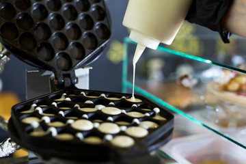 .Pouring dough on waffle maker. Preparing Hong Kong waffle