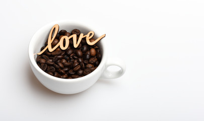 Ceramic cup with coffee beans and wooden word love. Romantic coffee break. Mug coffee beans on white background. Enjoy coffee drink. Date in cafe concept. Beverage consist caffeine