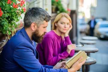Girl interested what he reading. Literature common interest. How to find girlfriend with common interest. Guide to dating. Meeting people with similar interests. Man and woman sit cafe terrace