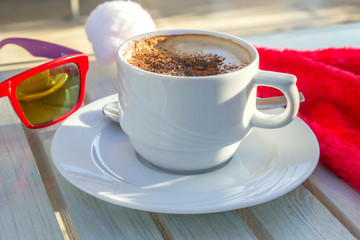 coffee cup and Santas hat and red glasses on a wooden table, christmas celebration