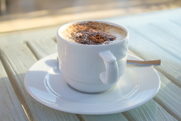 Cup of coffee with latte art of cardamon on wooden white table