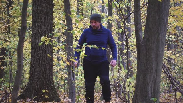 Bearded man in the forest with an ax slowing down. Forester chopping trees in the forest. Slow motion.
