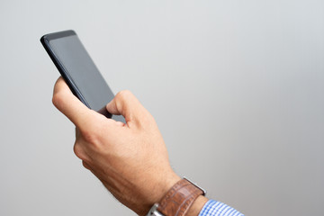 Closeup of man holding smartphone and touching its screen. Person texting on digital gadget....