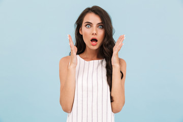 Excited shocked young woman posing isolated over blue background wall.
