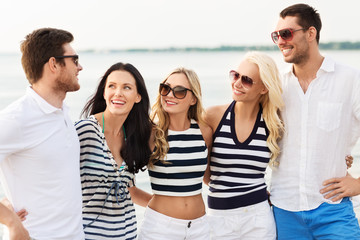friendship, summer holidays and people concept - group of happy friends in striped clothes on beach