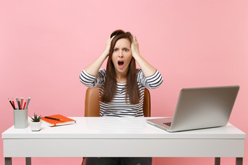 Irritated woman screaming clinging to head sit and work at white desk with contemporary pc laptop...