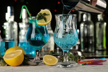 barman pours a blue lagoon cocktail from a shaker into a glass at the bar. cocktail preparation. © MK studio