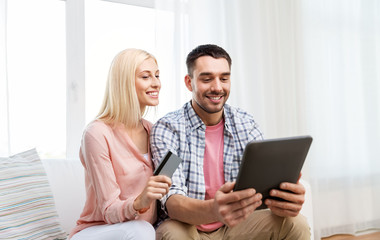 technology, online shopping and people concept - smiling happy couple couple with tablet pc computer and credit card at home
