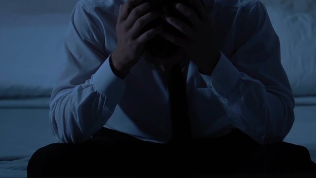 Sad thoughtful male sitting on bed, health problems and life difficulties stress